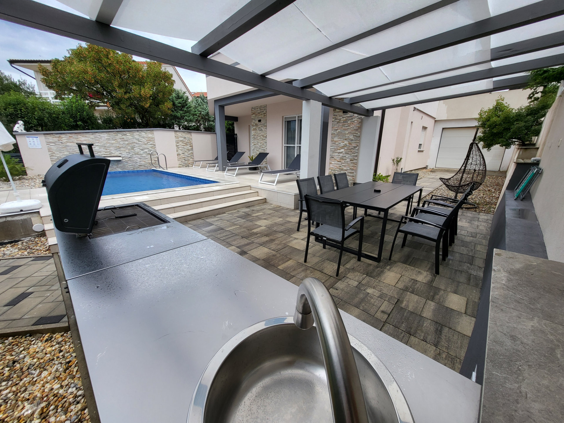 Poolside gazebo with barbecue, sink, and seating
