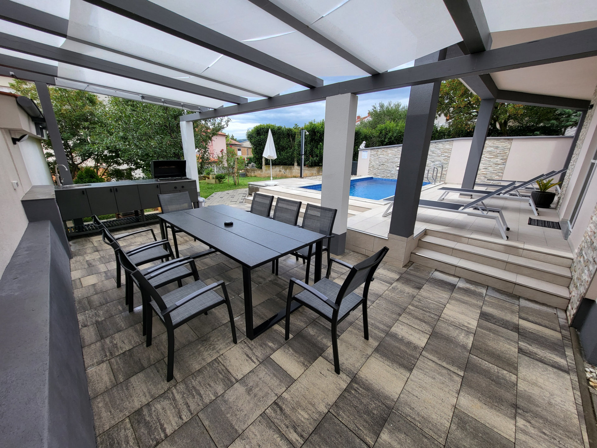 Poolside gazebo with barbecue, sink, and seating